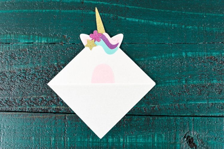 An assembled unicorn bookmark sitting on top of a dark green table