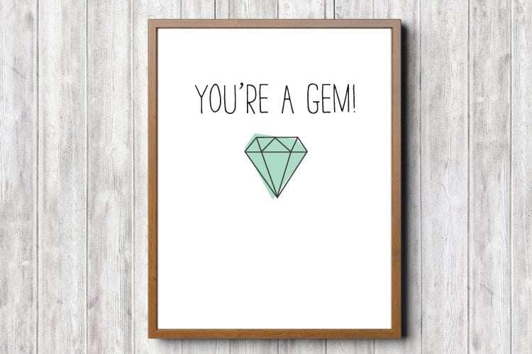 A wooden framed sign that has a green colored gem on it and text that says, \"You\'re a Gem\"