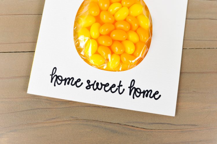 A card or sign that has a pineapple image on it with a pouch filled with candy and the saying, \"Home Sweet Home\"