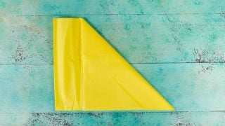 A piece of yellow tissue paper lying on an aqua blue table