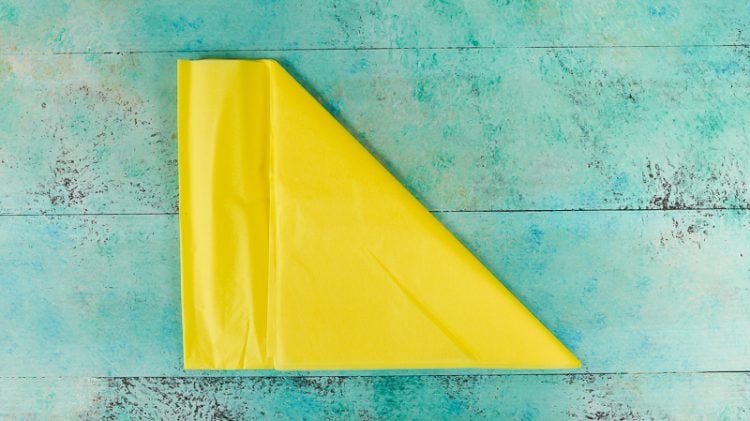 A piece of yellow tissue paper lying on an aqua blue table