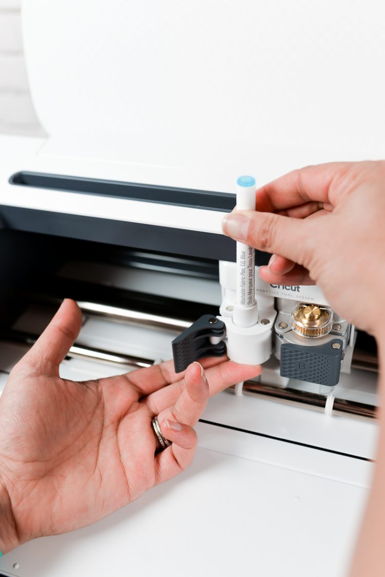 A person loading a pen into a Cricut machine