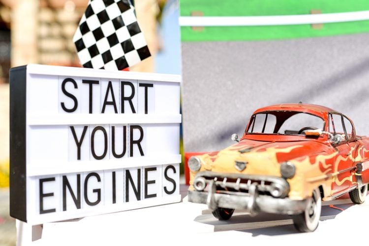 A close up of a toy car next to a sign that says, \'Start Your Engines\"