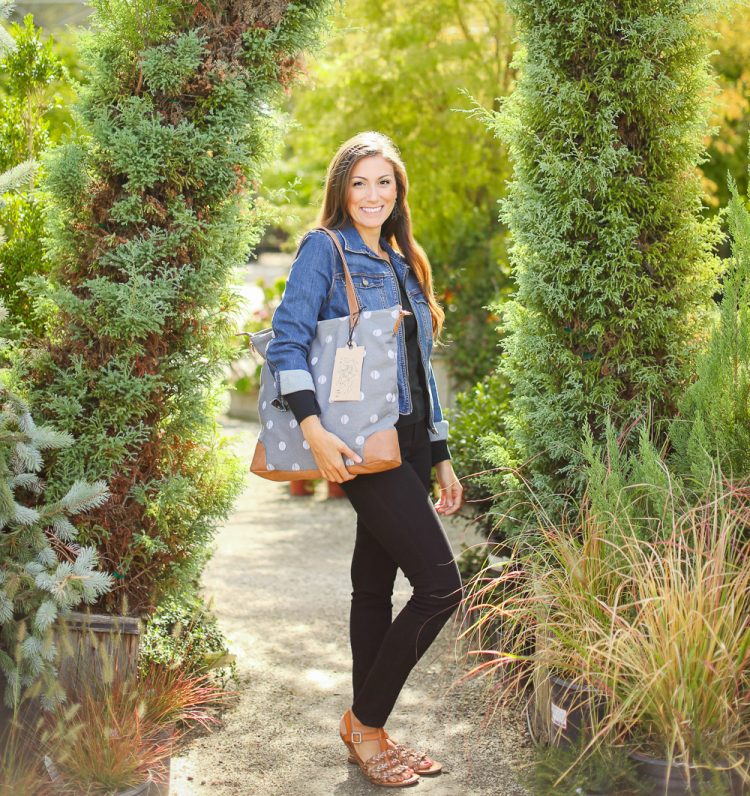 A woman holding a blue polka dot purse that has a tag hanging from it