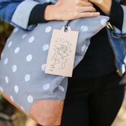 A close up of a woman holding a blue polka dot purse that has a tag hanging from it