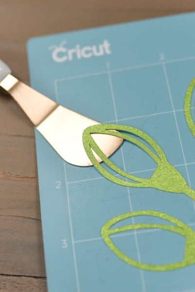 A design on a blue Cricut mat being lifted up off the mat with the Cricut spatula