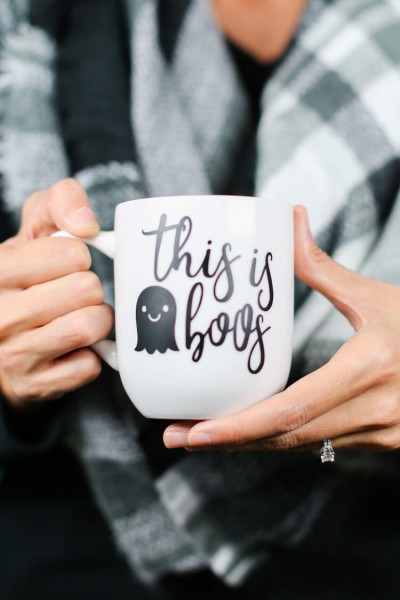 A close up of a person holding a cup, with decal of a ghost and the saying, "This is Boos"