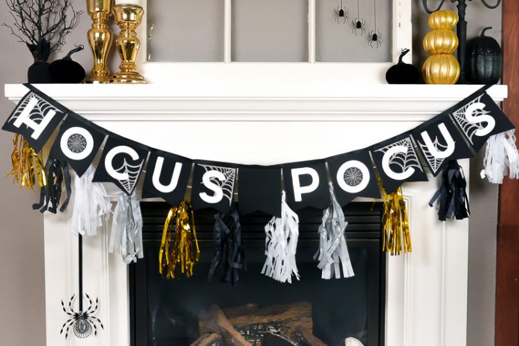 Close up of black, white and gold banner that says, \"Hocus Pocus\" and is hanging from a white fireplace mantel