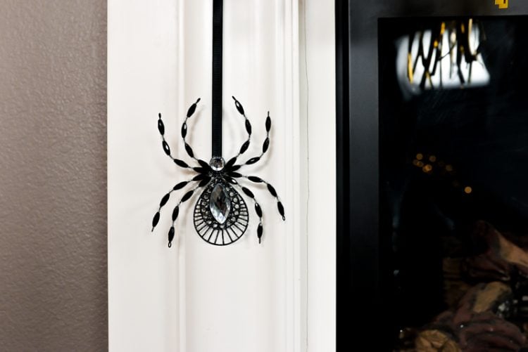 Close up of a black spider decoration hanging next to a fireplace