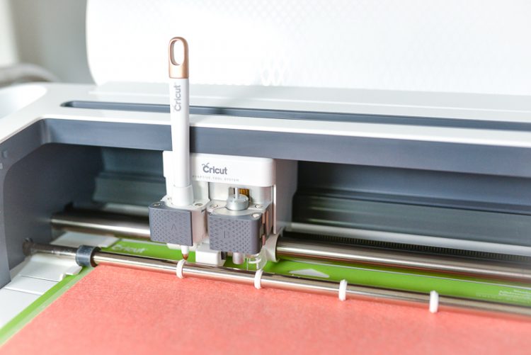 Cricut machine loaded with paper on a green mat