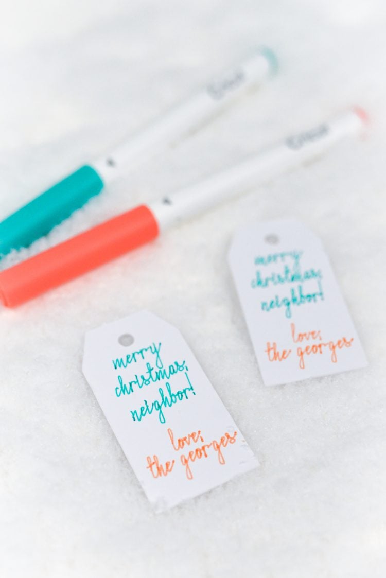 An aqua and a coral-colored marker next to two gift tags