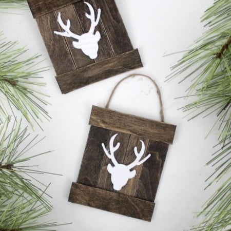 Two mini wooden pallets with an image of a deer silhouette on it and lying next to some greenery