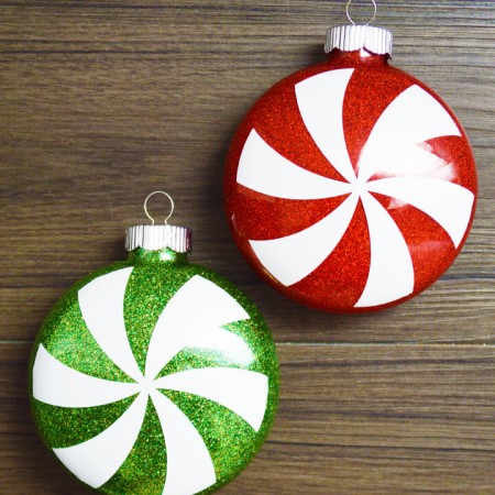 A close up of a red and of a green glittery peppermint candy ornament