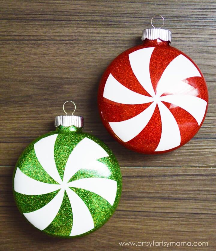 A close up of a red and of a green glittery peppermint candy ornament