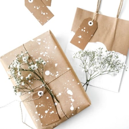 Gifts wrapped in brown paper with white splatters all over it and gift tags attached
