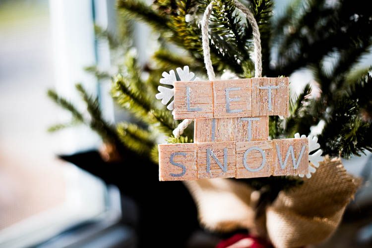An ornament hanging from a Christmas tree, and it says, \"Let It Snow\"