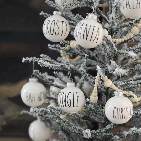 Small white ornaments hanging from a small tree and each ornament has one word on it such as, "Frosty", "Christmas", "Jingle", "Bah Humbug" and Santa