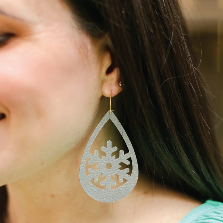 A close up of a girl wearing a snowflake design earring