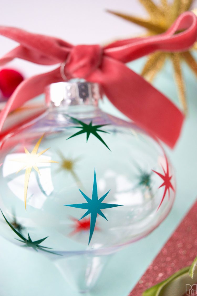 A close up of a glass ornament decorated with images of the star of Bethlehem and a bright red ribbon