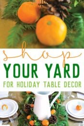 A table topped with a table runner decorated with greenery and candles and oranges along with place settings of plates, cutlery and water glasses along with advertising for shop your yard for holiday table decor from HEYLETSMAKESTUFF.COM