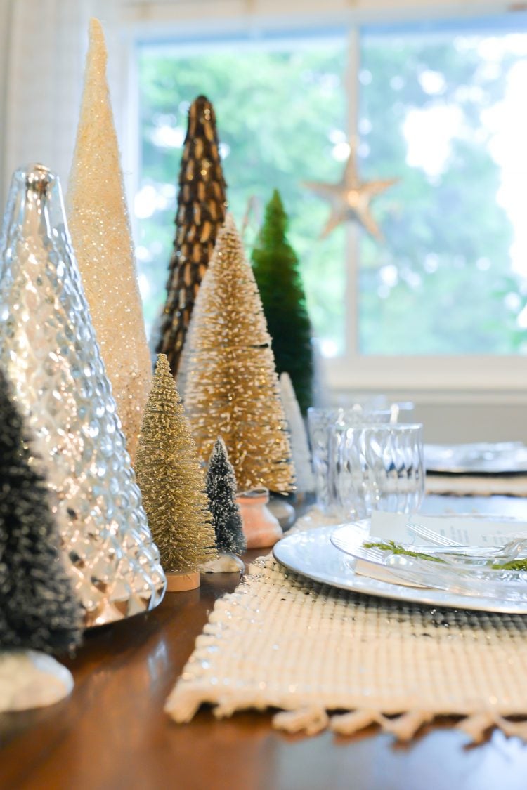 A group of sparkly, glittery trees sitting on a table next to a place setting