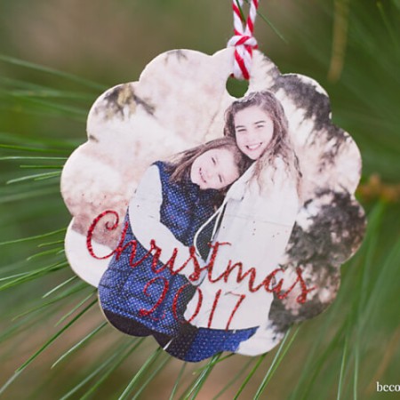 A wood ornament with a picture of two young girls and says, "Christmas 2017"