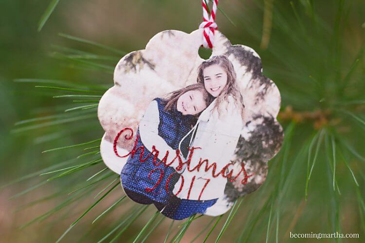 A wood ornament with a picture of two young girls and says, \"Christmas 2017\"