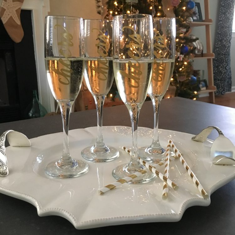 A table with champagne flutes decorated with the word \"Cheers\' on them