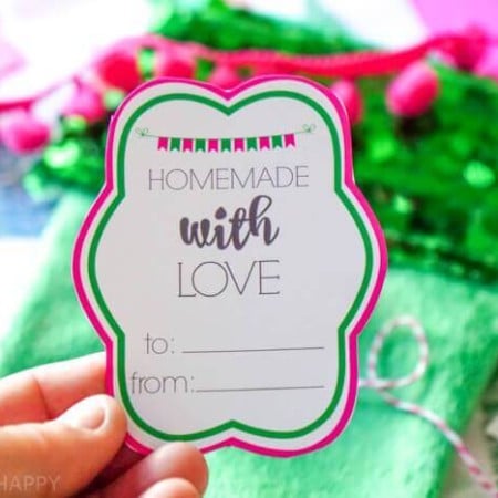 A hand holding a Christmas gift tag that says, "Homemade with Love"