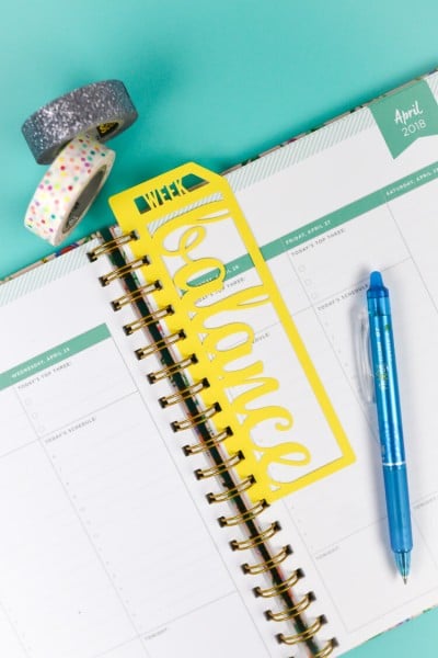 Two rolls of washi tape, a pen and a bookmark on a weekly planner