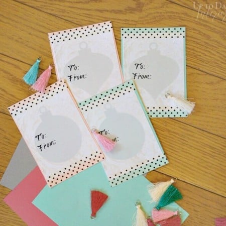 Images of Christmas gift tags and tiny colorful tassels laying on a table
