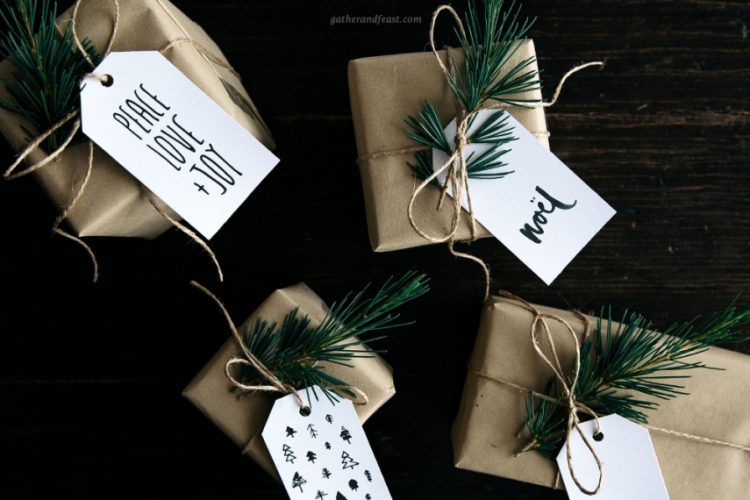 Gifts wrapped in brown paper and tied with twine with a piece of greenery and a gift tag attached