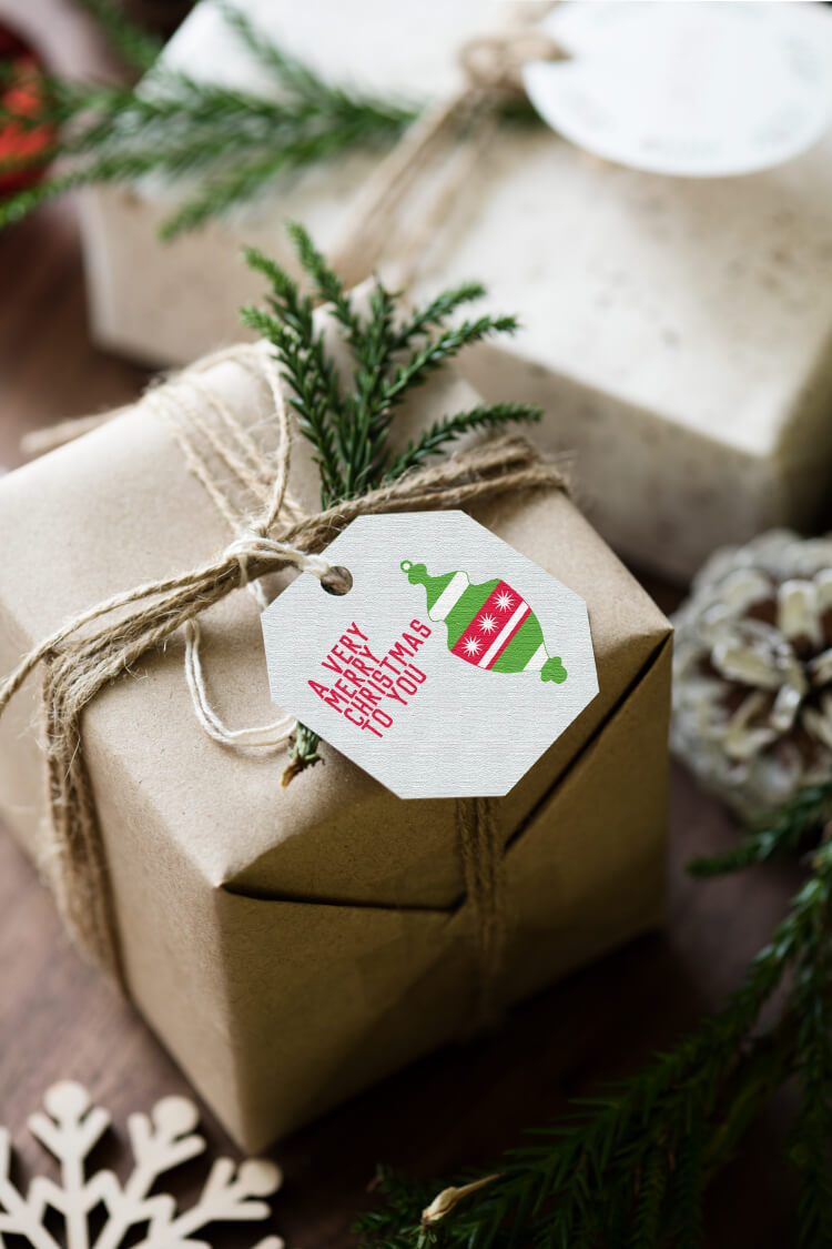 A gift wrapped in brown wrapping paper and tied with twine that has a piece of greenery attached to it and a gift tag that says, \"A Very Merry Christmas to You\"