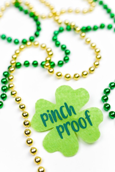 Gold and green colored beads on a table next to a green shamrock that says, "Pinch Proof"