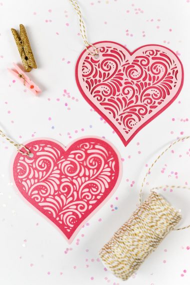 A roll of twine and two small clothespins next to two hearts cut out of paper