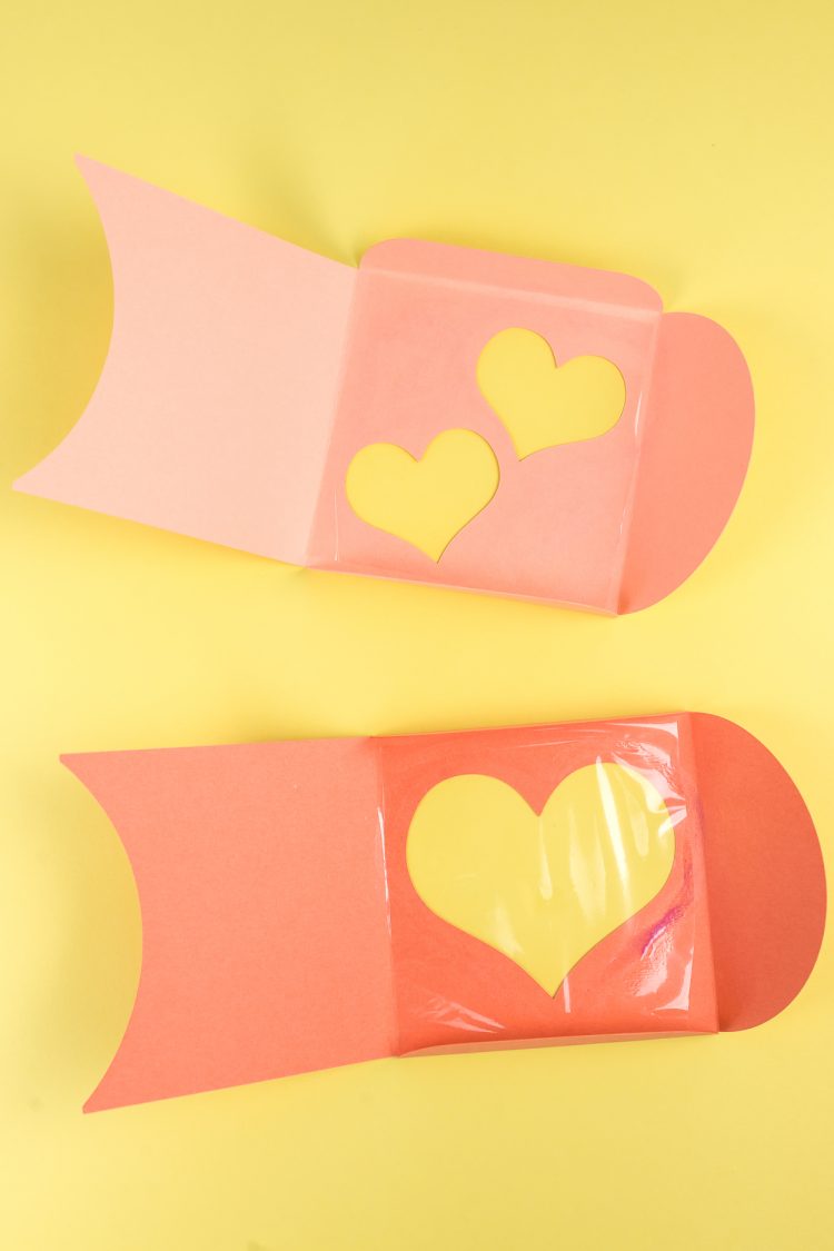 Two pieces of paper with cutout hearts with cellophane applied to them