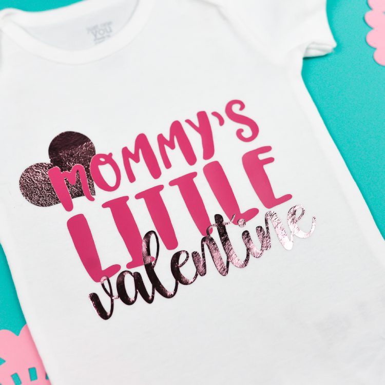 A white onesie decorated with a little heart and the saying, \"Mommy\'s Litte Valentine\"