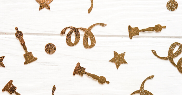 Gold glittery images of stars, dots swirls and Oscar award statues confetti 