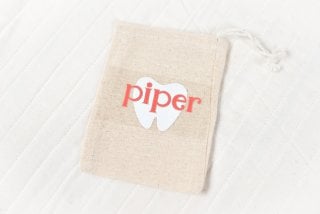 A close up of a small tan pouch, and the word piper and the image of a tool on transfer tape