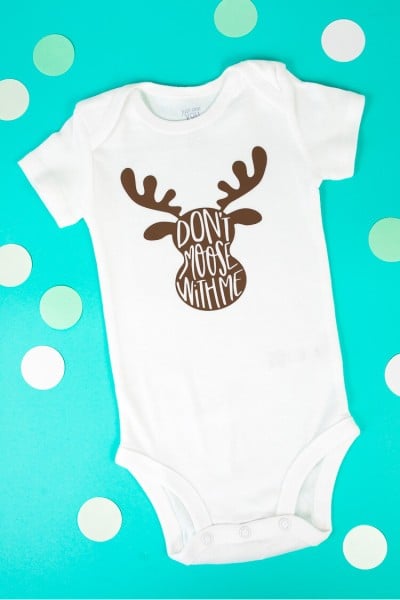 Paper polka dots around a white onesie that has an image on a moose on it and the saying, "Don't Moose with Me"