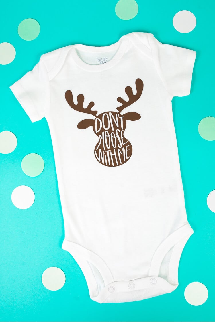 Paper polka dots around a white onesie that has an image on a moose on it and the saying, \"Don\'t Moose with Me\"