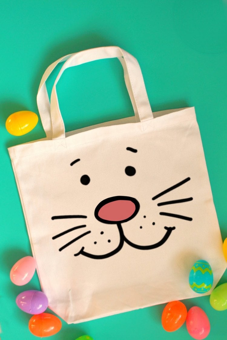 Plastic Easter eggs around a white canvas tote that is decorated with the face of a bunny