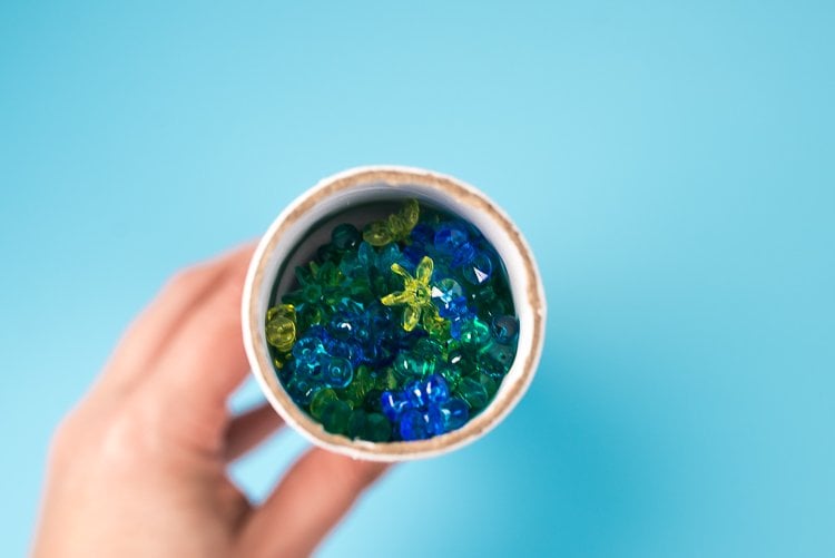 A hand holding a round tube with translucent beads inside of it