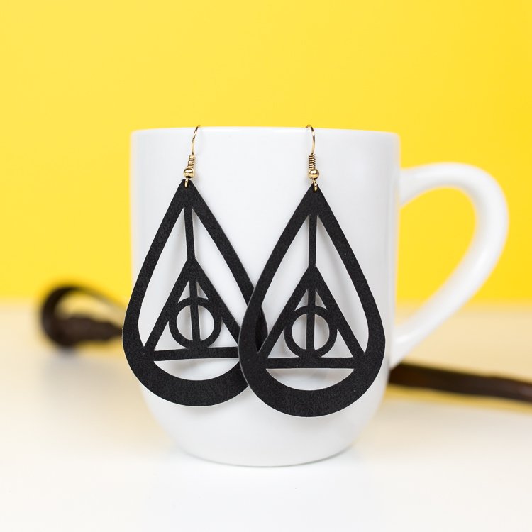 A pair of earrings hanging from a coffee mug