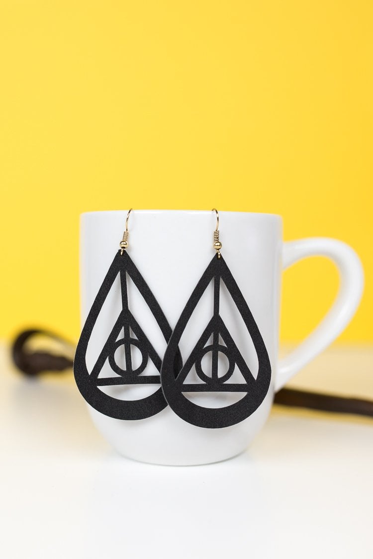 A pair of earrings hanging from a coffee mug