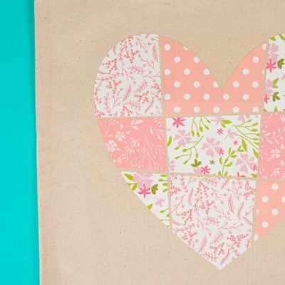 Close up of a tan colored canvas bag with an image of a patchwork heart on it