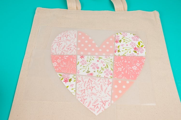 A tan colored canvas bag with an image of a patchwork heart on it