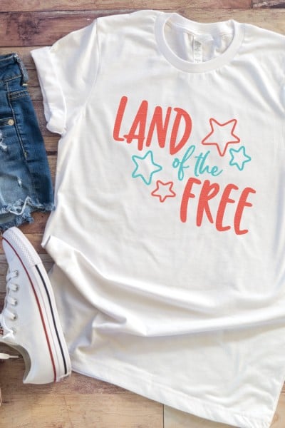 Blue jean shorts, a tennis shoe and a white t-shirt decorated with an image of stars and the saying, 'Land of the Free"