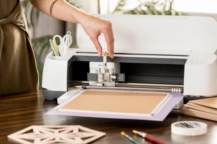 A woman standing next to a Cricut machine loading the Cricut knife blade