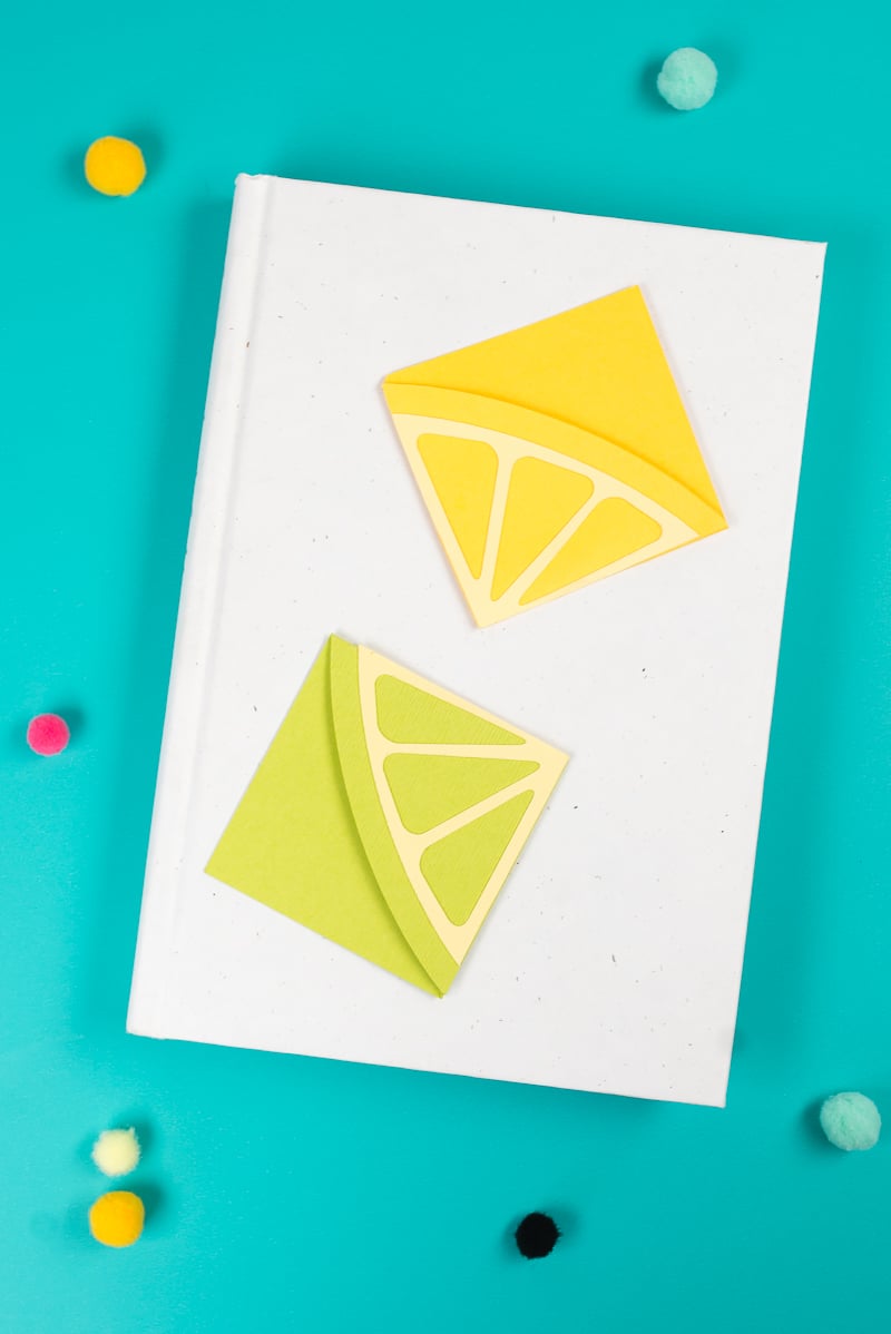 A book with two paper bookmarks made out of a lemon and a lime design